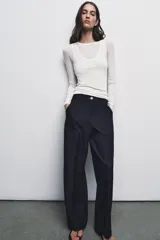 Pantalón de tiro alto con pernera recta, confeccionado en denim oscuro. Presenta nervios marcados en el delantero, bolsillos frontales tipo parche y cierre frontal con cremallera y botón.