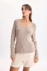 Sweater de punto color beige con hilos de lurex, escote en V y mangas largas con costuras en los hombros.