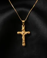 Dije de acero dorado con diseño de cruz con figura de Cristo en relieve.
