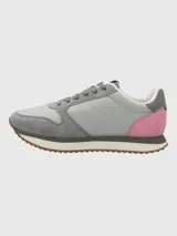 Zapatillas casuales de diseño contemporáneo, confeccionadas en una combinación de cuero y material textil. Presentan una base en tonos grises con detalles en rosa en el talón y suela dentada de goma en color marrón.
