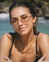 Lentes de sol con marco rectangular dorado y lentes color rosa.