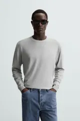 Jersey color crudo de tejido de punto, con cuello redondo y mangas largas. Corte amplio y terminaciones en rib.