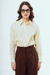 Camisa de manga larga color amarillo con rayas verticales oscuras, cuello camisero clásico y cierre frontal abotonado.