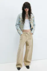 Jeans de tiro medio confeccionados en denim con diseño de cintura doblada y trabillas, cinco bolsillos, cierre frontal con cremallera y botón metálico, lavado claro y roturas en las rodillas.