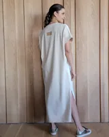 Vestido largo color crema, de corte recto y holgado, con cuello redondo y mangas cortas. Presenta aberturas laterales en la falda.