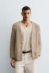 Cardigan de punto grueso color beige, con cuello pico, manga larga y cierre frontal de botonadura.