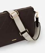 Bolso tipo bandolera de color marrón oscuro, con textura de cuero sintético (PU) y patrón geométrico acolchado en la parte frontal. Cuenta con herrajes dorados, cierre superior y una correa ancha de tela bicolor (beige y marrón) ajustable.