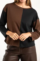 Sweater de algodón con diseño bicolor en bloques, combinando tonos marrón y negro. Presenta cuello redondo, mangas largas y una textura acanalada.