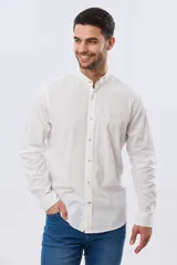 Camisa de lino y algodón color beige, de manga larga, con cuello mao y cierre frontal con botones. Presenta un pequeño bordado al tono en el pecho.