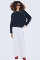 Jersey de punto de manga larga con cuello redondo, diseño en color azul marino con detalles de vivo en color blanco en el cuello y las costuras de las mangas.