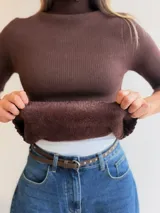 Media polera de tejido acanalado en color crema, con cuello alto y terminaciones con borde ondulado. Cuenta con un interior suave y cálido, ideal para los días fríos.