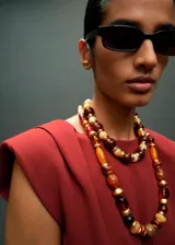 Blusa color bordó con hombreras marcadas, cuello barco y diseño recto sin mangas.