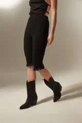 Calza negra capri ajustada con detalle de encaje en el ruedo.