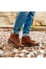 Bota tipo borcego Pegada en cuero marrón, con cordones frontales y suela de goma.
