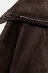 Cazadora bomber marrón de efecto gamuza, con cuello de solapa amplia, manga larga, bolsillos delanteros y cierre frontal asimétrico con cremallera metálica.