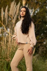 Buzo color beige de cuello alto y mangas abullonadas.