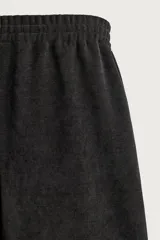 Pantalón jogger de corte relajado en color negro, confeccionado en tejido con elasticidad. Presenta cintura elástica con cordón ajustable y bolsillos laterales decorados con tachas metálicas.