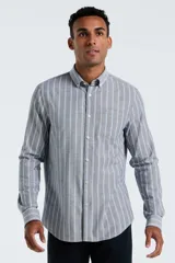 Camisa de manga larga confeccionada en tejido Oxford, con diseño de rayas verticales en tonos gris y azul claro. Presenta cuello abotonado, cierre frontal con botones y un bolsillo en el pecho.