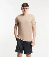 Remera deportiva de hombre con tecnología dry fit, cuello redondo y manga corta. Presenta un diseño liso en color beige con una pequeña etiqueta decorativa en el dobladillo.