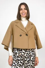 Capa de paño color camel con diseño de doble botonadura frontal y solapas clásicas. Presenta un corte estructurado y mangas abiertas tipo capa que ofrecen libertad de movimiento.