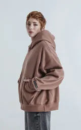 Hoodie oversize de corte crop en color marrón, confeccionado en frisa gamuzada de algodón. Presenta capucha forrada, bolsillo tipo canguro frontal y puños y ruedo acanalados.
