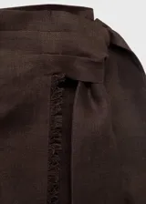 Falda midi de lino color marrón, de corte recto y diseño cruzado con tiro medio y detalle de nudo en la cintura.