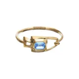 Pulsera semirrígida bañada en oro 18k con diseño orgánico y cristal azul facetado de corte rectangular en el centro.