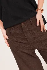 Pantalón de lino marrón, de tiro alto y corte wide leg, con bolsillos delanteros y cierre frontal de botón y cremallera.