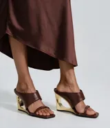 Sandalias tipo mule de color marrón, con tiras anchas en el empeine, tira fina separadora de dedos, puntera cuadrada y taco chino calado con acabado dorado metalizado.