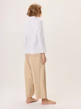 Remera blanca de manga larga con cuello alto, corte holgado y costuras verticales decorativas en el frente.