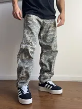 Pantalón de corte baggy con estampado de camuflaje digital en tonos grises y verdes. Presenta un diseño holgado y recto, ideal para un estilo urbano.