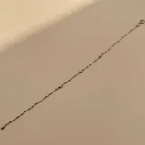 Pulsera de cadena fina de plata con pequeñas cuentas esféricas de oro distribuidas a lo largo de la pieza.