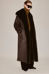 Abrigo largo de Zara Woman Collection en color marrón chocolate, con cuello de solapa amplio, mangas largas y cinturón ajustable del mismo tejido. Presenta detalles de forro interior y acabados en efecto pelo a tono en cuello, puños y bordes frontales.