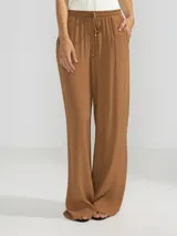 Pantalón palazzo negro de crepe con cintura elastizada, bolsillos laterales y terminaciones en cobre.