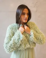 Chaqueta cropped de textura peluda en color verde agua, con diseño de manga larga y acabado suave. Ideal para complementar outfits de ocasión.