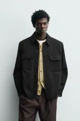 Sobrecamisa relaxed fit color beige con tejido elástico, cuello solapa, manga larga con puños abotonados, bolsillos de plastrón con solapa en el pecho, bolsillos laterales de vivo en la cadera y cierre frontal de botones.