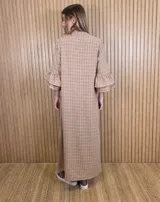 Vestido largo tipo túnica de color azul con estampado a cuadros blancos, cuello mao con escote en V y botones frontales parciales. Presenta mangas tres cuartos con volados en cascada.
