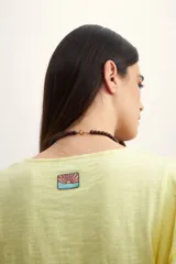 Remera color amarillo pastel con cuello redondo y mangas cortas con volados.
