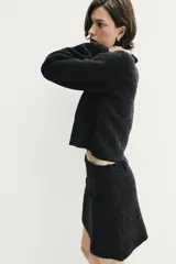 Falda corta de tiro medio confeccionada en tejido de punto, con diseño de silueta recta, cintura con trabillas y detalles de falsos bolsillos de vivo en la parte frontal.