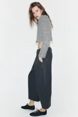 Pantalón de tiro medio con diseño balloon de pierna ancha. Presenta pliegues frontales, costuras horizontales marcadas en las piernas, bolsillos laterales y cierre frontal con cremallera y botón.