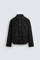 Sobrecamisa de corte relajado confeccionada en tejido efecto piel color negro. Presenta cuello solapa, cierre frontal con botones metálicos, mangas largas con puños abotonados y dos bolsillos de plastrón con solapa en el pecho.