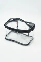 Neceser transparente con cierre superior y ribetes negros.