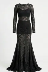 Vestido largo de encaje negro con transparencias, de corte ajustado al cuerpo, manga larga y falda con caída fluida.
