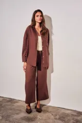 Camisa oversize color marrón, confeccionada en mezcla de viscosa y lino, con cuello clásico, cierre frontal con botones y un bolsillo aplicado en el pecho.