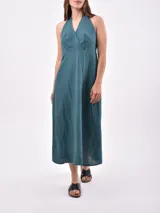 Vestido midi de color verde petróleo, con escote halter cruzado y espalda descubierta. Presenta un corte entallado en la cintura y falda con vuelo.