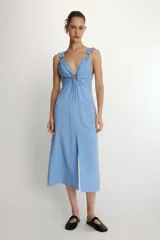 Vestido midi de corte recto con estampado de rayas verticales en tonos azul y blanco. Presenta escote en pico con detalle de abertura ajustable mediante lazada frontal, tirantes anchos con acabado fruncido y cierre lateral con cremallera oculta.