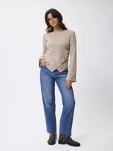 Jean de corte recto y tiro medio, con diseño clásico de cinco bolsillos. Presenta un lavado azul medio y terminación de ruedo desflecado.