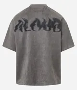 Remera oversized masculina de media malla con toque gamuza, color gris oscuro con efecto lavado. Presenta un bordado blanco en forma de media luna en el pecho y un estampado lettering en la parte delantera y trasera.
