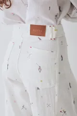 Pantalon de corte wide leg y tiro alto, confeccionado en tela con estampado deportivo que incluye pelotas de futbol y raquetas de tenis en tonos verde, rosa y beige.