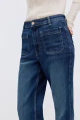 Jean de denim color azul oscuro, con corte wide leg de tiro alto, bolsillos delanteros de parche y pliegues marcados al frente.
